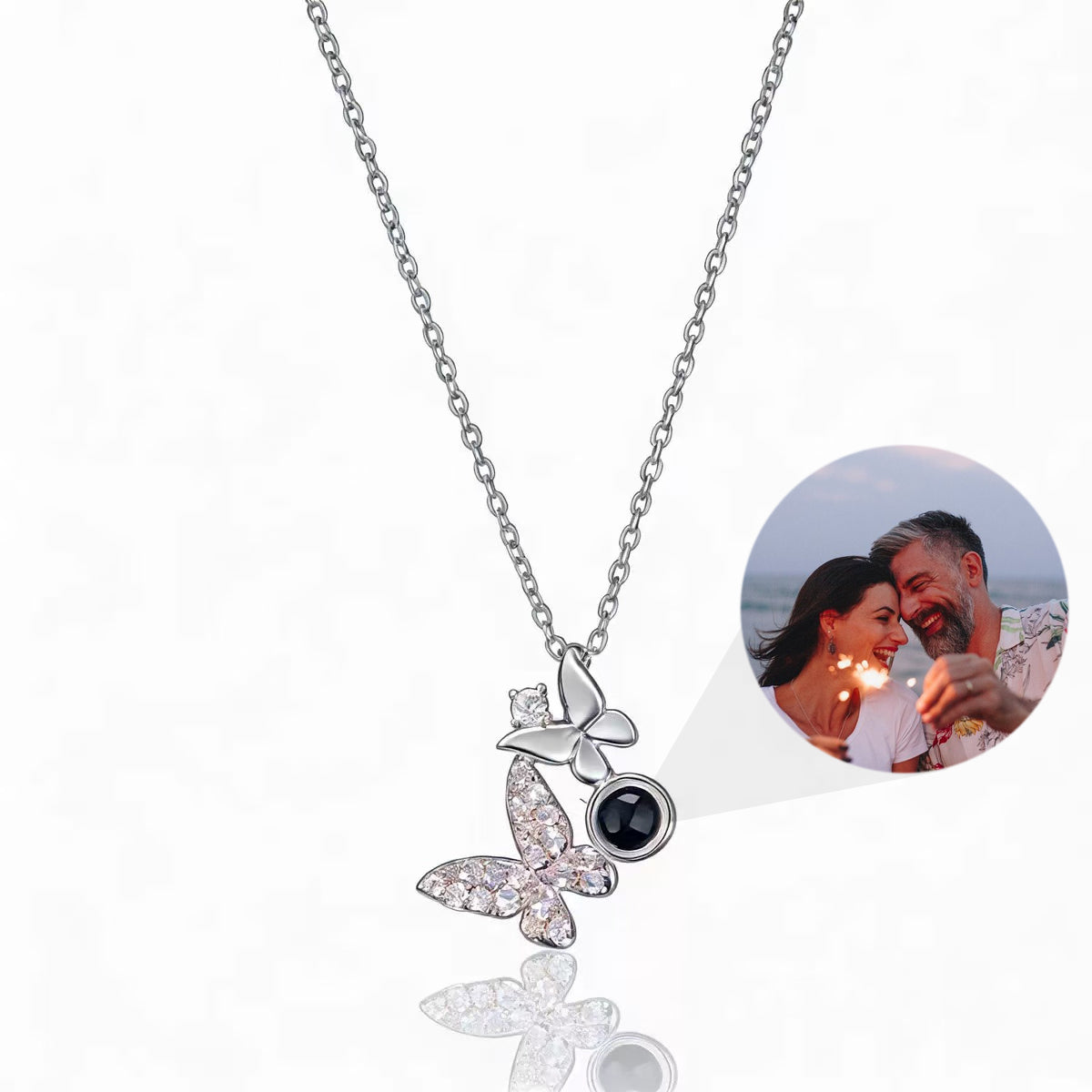 Custom butterfly-shaped photo projection necklace in silver, with a hidden projection bead displaying a photo of a couple