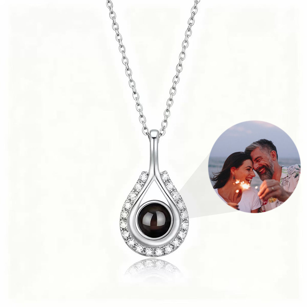 Custom teardrop-shaped photo projection necklace in silver, with a hidden projection bead displaying a photo of a couple