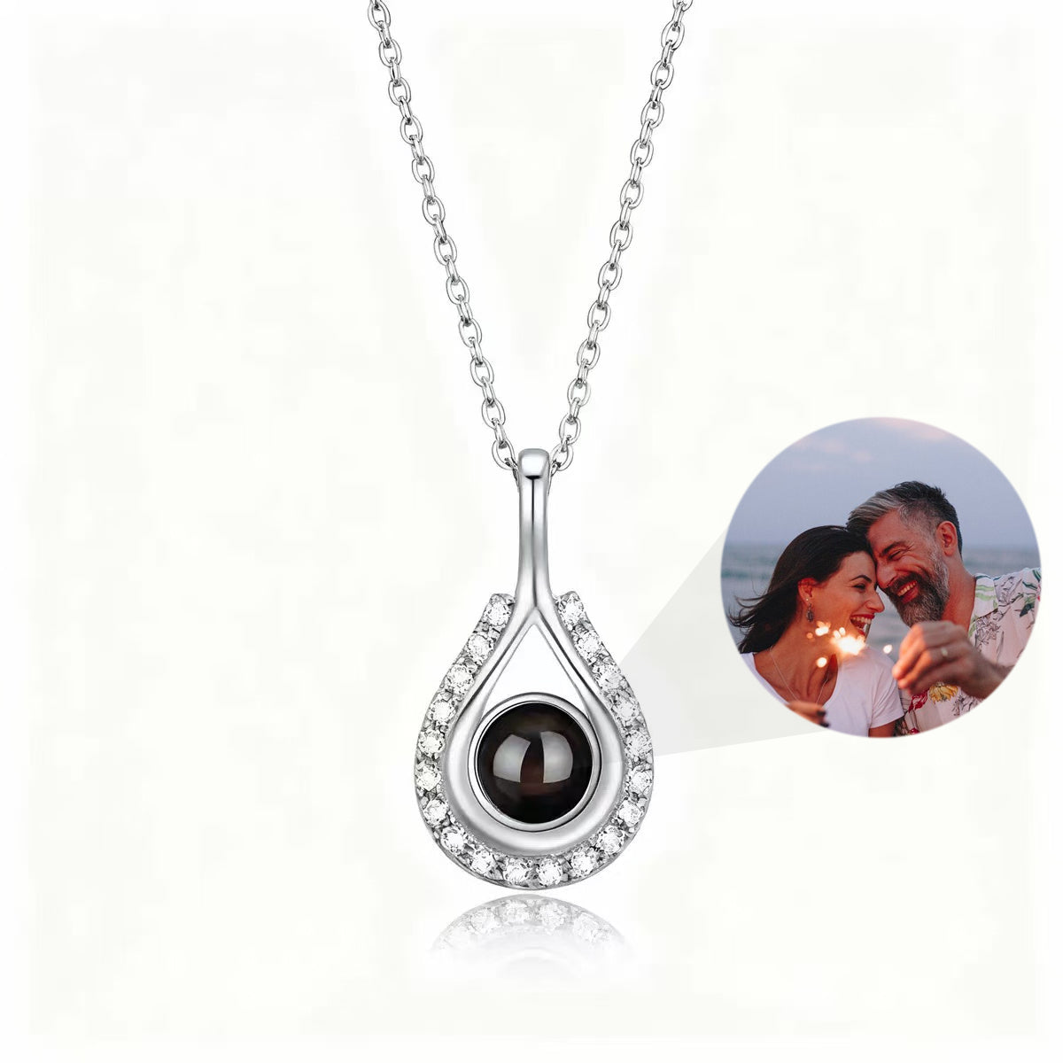 Custom teardrop-shaped photo projection necklace in silver, with a hidden projection bead displaying a photo of a couple